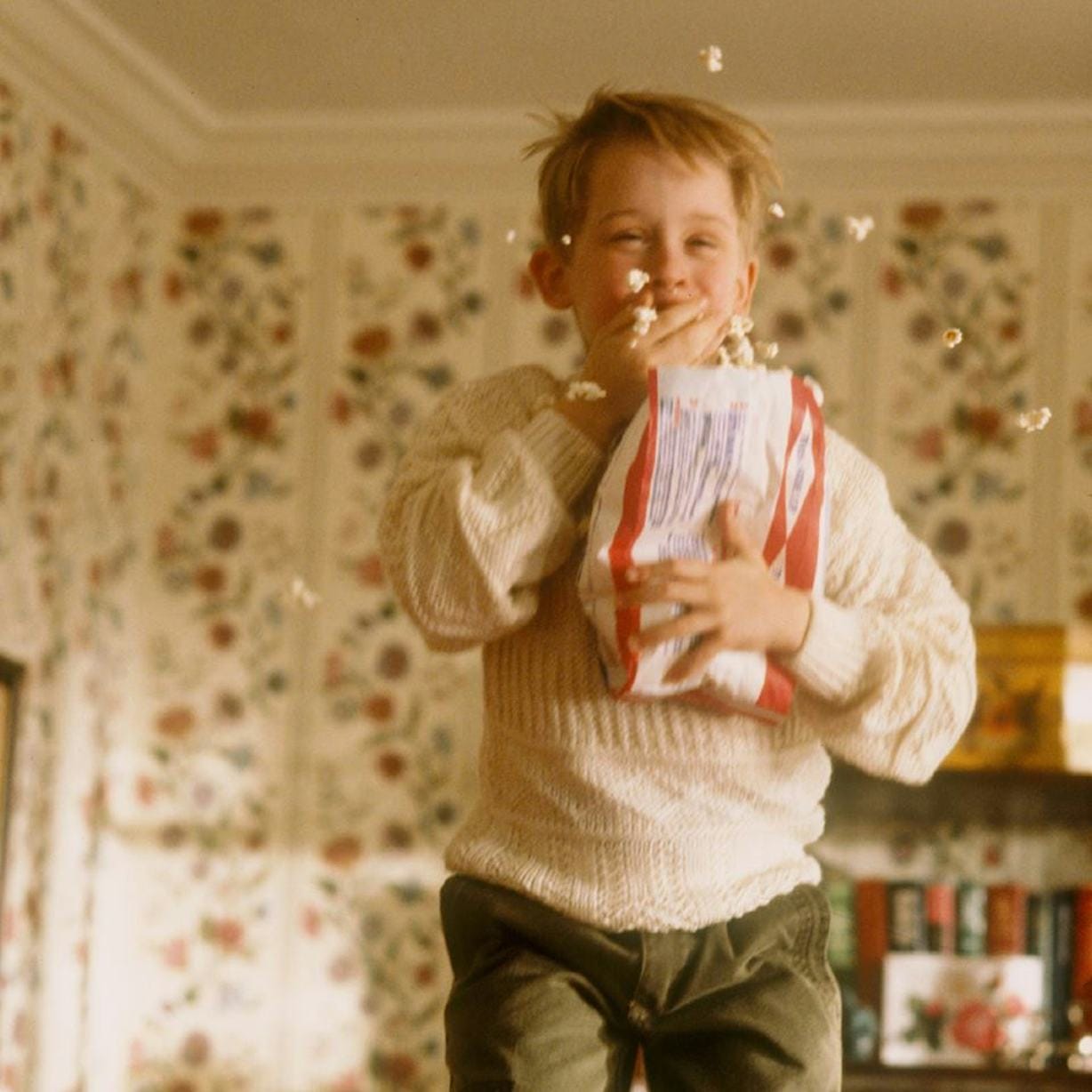 Macaulay Culkin como Kevin en la película Home Alone, saltando y comiendo palomitas