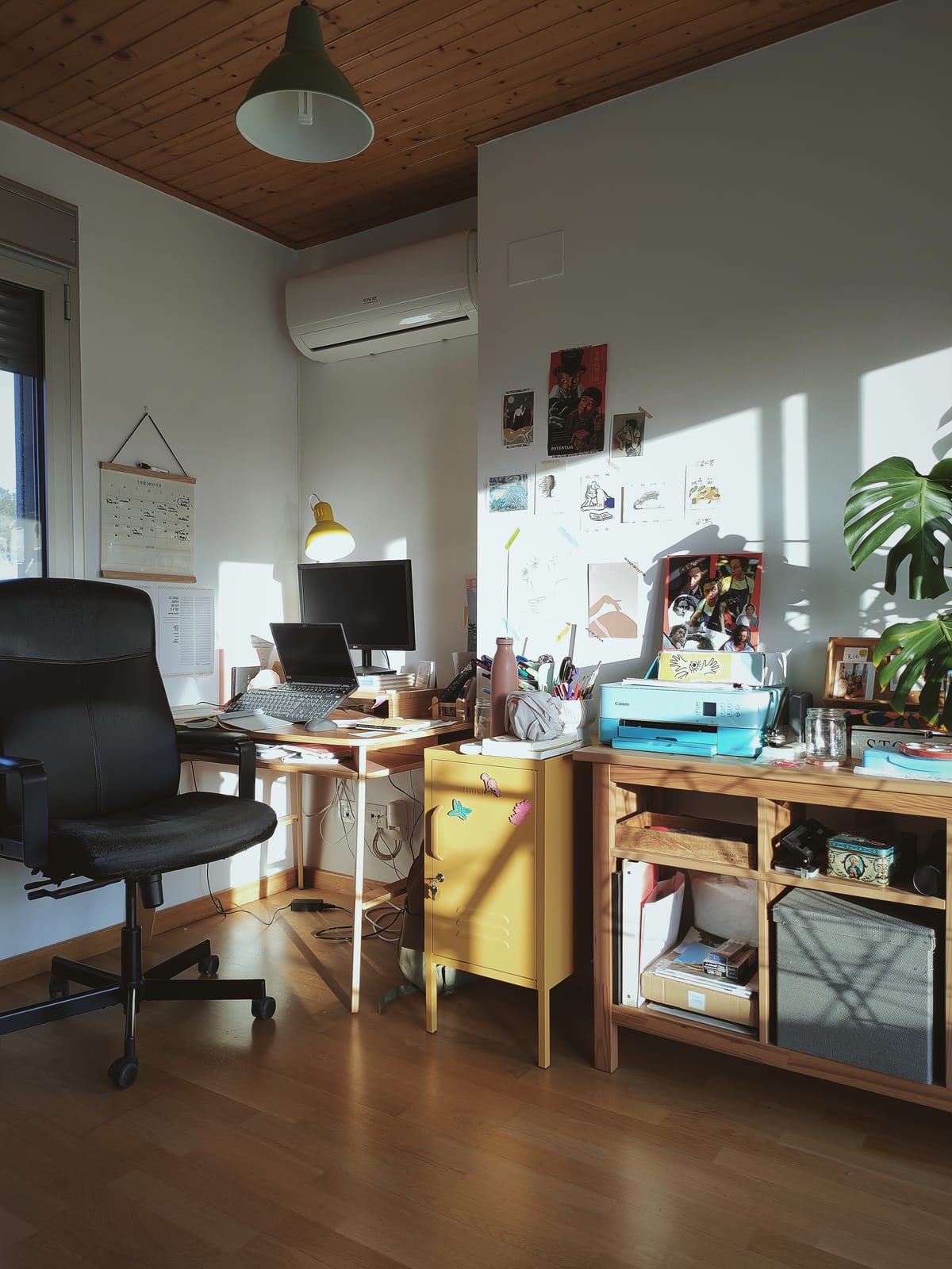 un espacio de trabajo compuesto por un archivador color mostaza, una cajonera de madera, un escritorio y una silla de oficina negra
